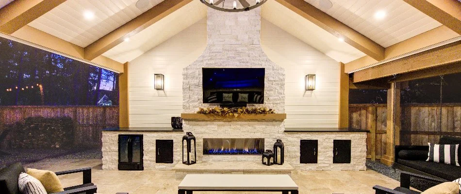 White stone outdoor fireplace under a pavilion.